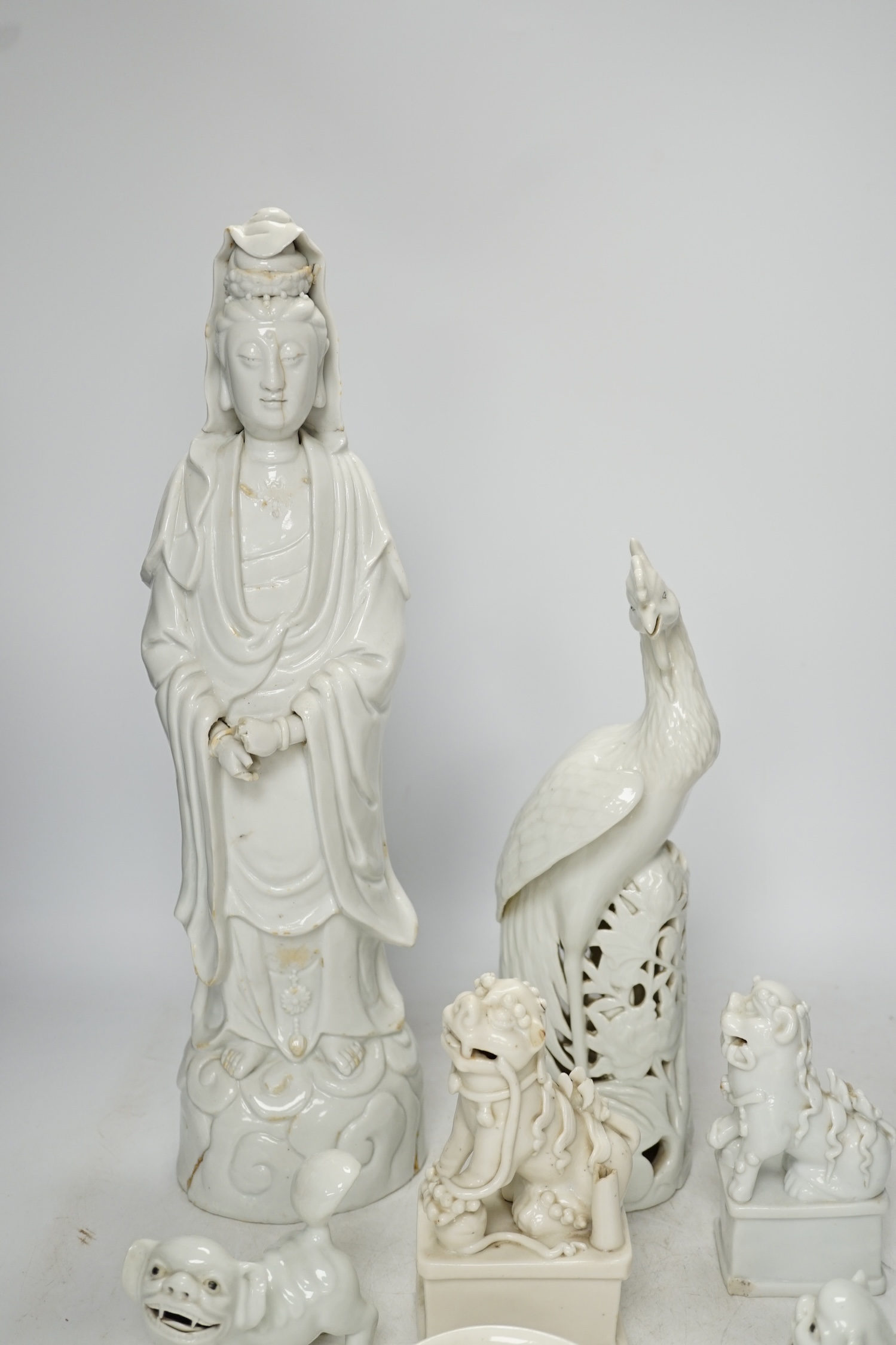 Seven Chinese blanc de chine pieces to include a pair of lion dogs and a phoenix, 17th century and later, largest 44cm high. Condition - varies, poor to fair